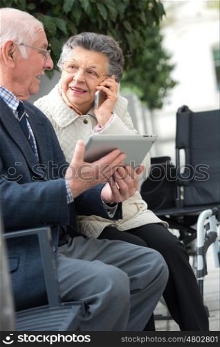old disabled woman and his husband with digital tablet