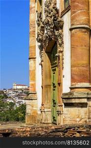 Old door and facade of historic baroque church with the city of Ouro Preto in Minas Gerais in the background. Old door and facade of historic baroque church with the city of Ouro Preto