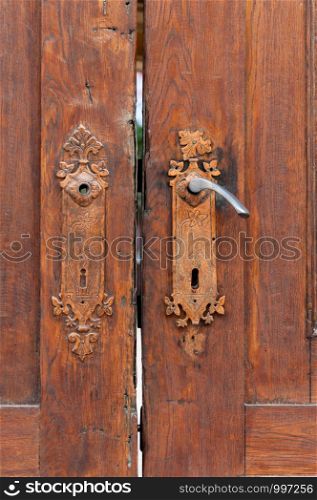 Old door knob on a wooden door. Weathered, broken and repainted.