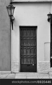 Old door with metal pattern and old fashioned street light. Black and white.