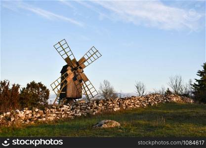 Old dry stone wall and a traditional windmill by fall season at the island Oland in Sweden