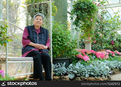 old elder woman resting in flower garden. asian elderly female relaxing in park. senior leisure lifestyle