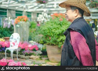 old elder woman resting in flower garden. asian elderly female relaxing in park. senior leisure lifestyle