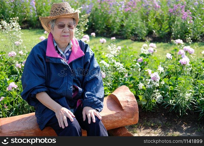old elder woman resting in garden. asian elderly female relaxing outdoors. senior leisure lifestyle