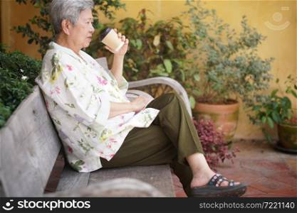 old elderly senior elder woman drinking hot coffee in garden. mature retirement lifestyle