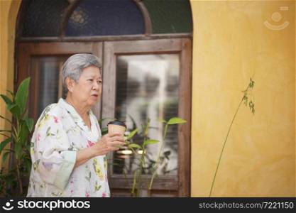 old elderly senior elder woman drinking hot coffee in garden. mature retirement lifestyle