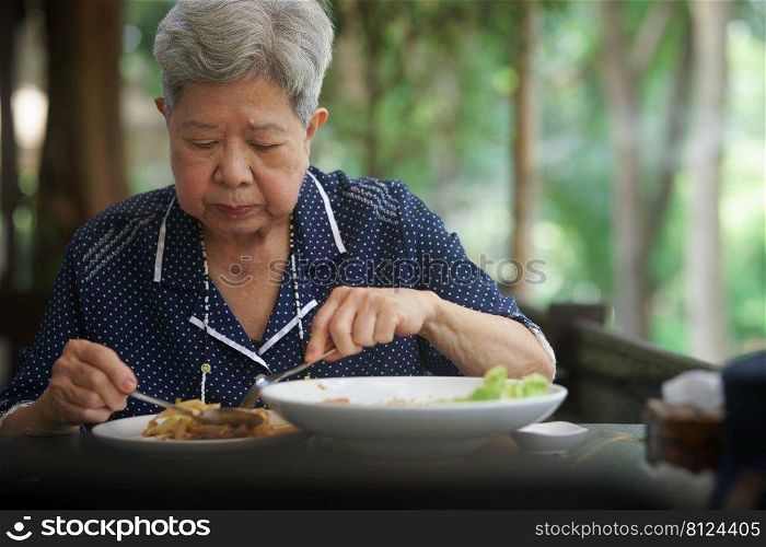 old elderly senior elder woman eating food on terrace. mature retirement lifestyle