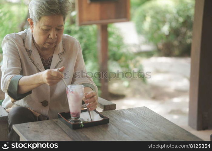 old elderly senior elder woman eating ice cream on terrace. mature retirement lifestyle