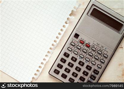 Old electronic calculator and blank square sheet of paper
