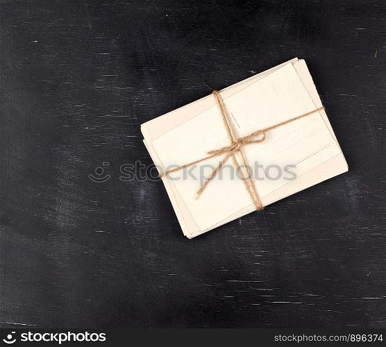 old empty white paper cards tied with a rope on a black wooden background, copy space