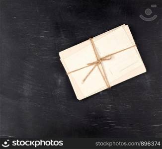 old empty white paper cards tied with a rope on a black wooden background, copy space