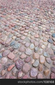 Old European rounded cobblestones of various shapes and sizes in perspective.