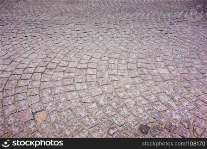 Old European square cobblestones arranged in arcing curved pattern.