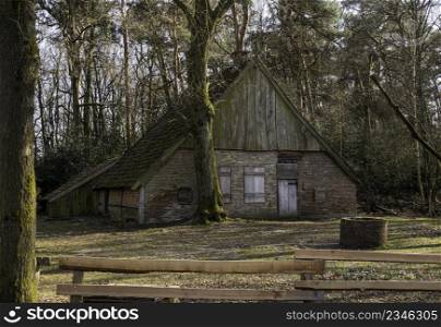 old farm in the netherlands near burse in the nature reserve burserzand, with a wooden fence in the front and a forest in the background. old barn in the forest in the netherlands during winter
