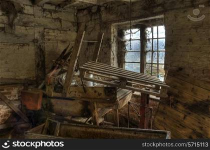 Old farm machinery stacked in the corner of a cowhouse, Worcestershire, England.