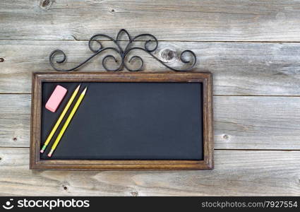 Old fashion chalkboard, pencils and eraser on rustic wood. Layout in horizontal format.
