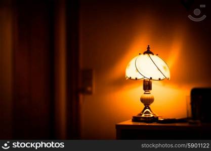 Old fashioned antique lamp glowing on a table