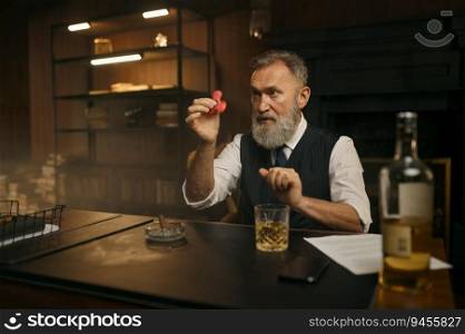 Old-fashioned elegant senior businessman playing spinner toy while sitting at work table over home office background. Old-fashioned elegant senior businessman playing spinner toy