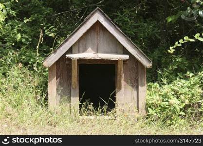 Old fashioned wooden dog house sitting in grass.