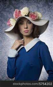 old fashioned young woman with blue dress and a white hat with some flower as ornament