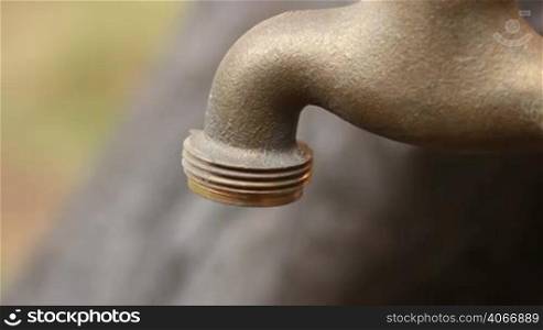 Old faucet dripping. Iron old fashioned garden fountain. A good clip for ecology or saving money ideas. Saving water for a sustainable environment.