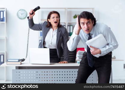 Old female boss and young male employee in the office  