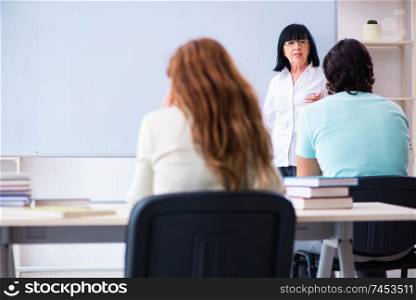 Old female english teacher and students in the classroom