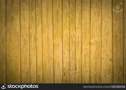 Old fence painted in yellow, wooden background