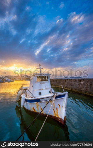 Old fishing boat in port of Naousa on sunset with dramatic sky. Paros lsland, Greece. Old fishing boat in port of Naousa on sunset. Paros lsland, Greece