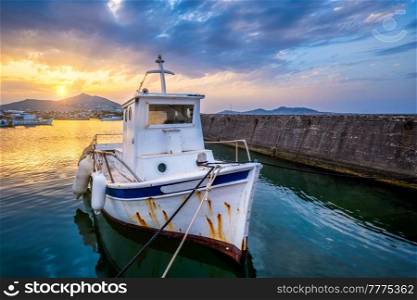 Old fishing boat in port of Naousa on sunset with dramatic sky. Paros lsland, Greece. Old fishing boat in port of Naousa on sunset. Paros lsland, Greece