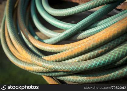 Old garden hose curled up in a pile and stained by years in the weather