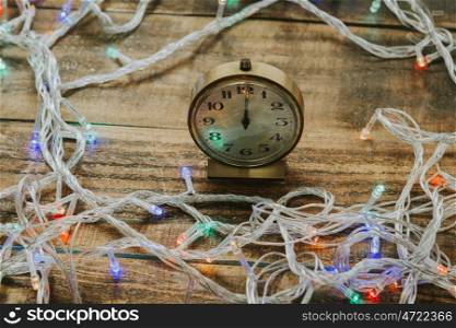 Old golden alarm clock with lights for decoration on a wooden background