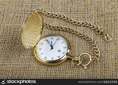 old golden pocket watch on burlap background
