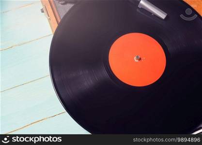 Old gramophone with a vinyl record on green wooden table, top view.