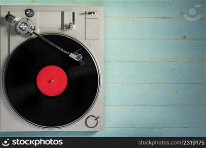 Old gramophone with a vinyl record on rustic wooden table, top view.