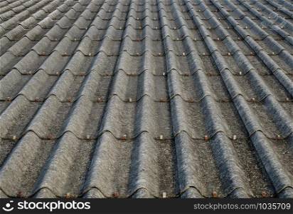 Old gray concrete roof tiles with dirt stains all over the sheet has been used for a long time, one point perspective view.