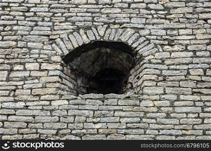 Old gray stone wall with embrasure in Krom (Kremlin) of Pskov, Russia