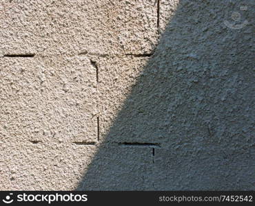 Old grey stone masonry wall texture made of foam blocks or airblocks split on two sides light and shadow. Abstract plastered surface. Grunge, weathered construction structure.