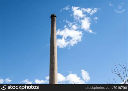 Old grunge weathered disused chimney on blue sky background