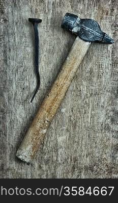 old hammer and a rusty nail on a blackboard