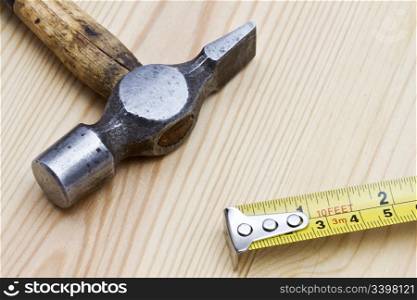 Old hammer and tape measure on wood background