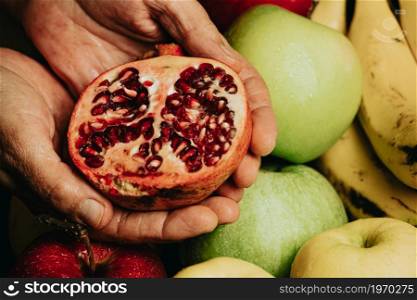 Old hands grabbing a passion fruit over a full of fruits background with water drops over the apple, healthy concept shot