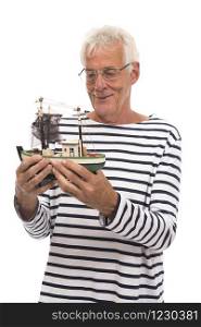 Old happy sailor holding wooden model fishing boat