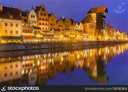 Old harbour crane and city gate Zuraw in old town of Gdansk, Dlugie Pobrzeze and Motlawa River at night, Poland