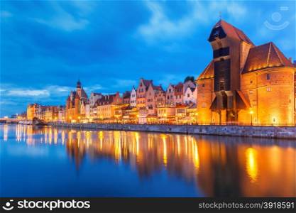Old harbour crane and city gate Zuraw in old town of Gdansk, Dlugie Pobrzeze and Motlawa River at night, Poland