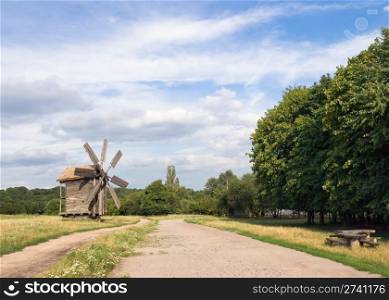 Old historical obsolete windmill near country road in field