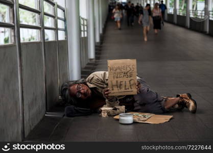 Old Homeless man or beggar carry help plate to ask for money during covid-19 or coronavirus disease. Broke man got less donation due to social distancing, quarantine, work from home.