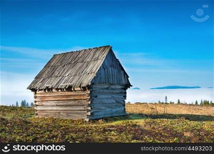 Old house in front of beautiful nature with clouds ocean, field of grass and mountains
