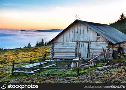 Old house in front of beautiful nature with clouds ocean, field of grass and mountains