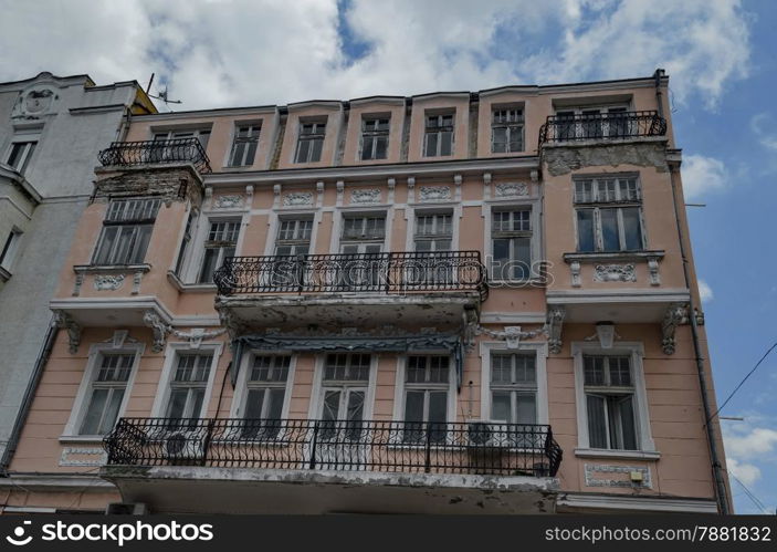 Old house with interesting facade.Metal ornament fence of balcony and gypsum figure of wall. Must to be renovate.